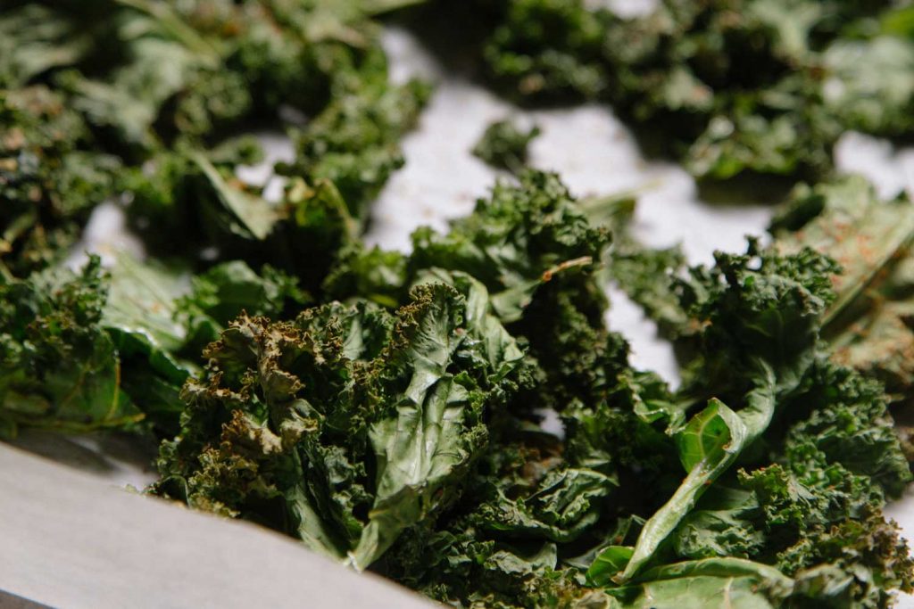 [Bake kale chips are displayed on a baking sheet.]